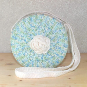 Crochet round purse in multicolored blue-green colors with a white rose, zipper top and white strap.