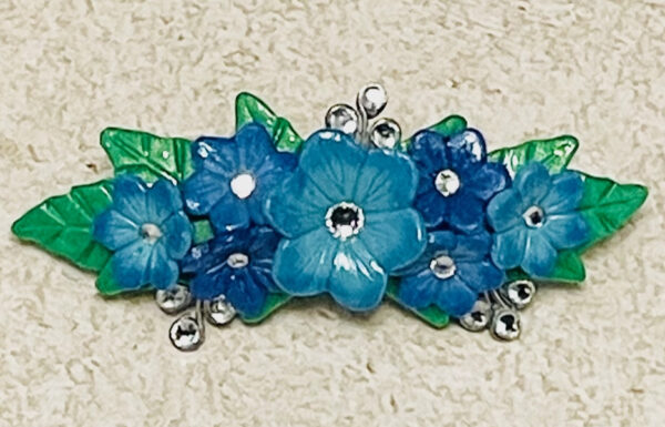 Blue clay flowers barrette with rhinestones and green leaves.