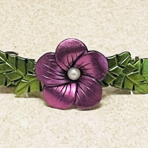 Purple chrome color flower barrette with green leaves.