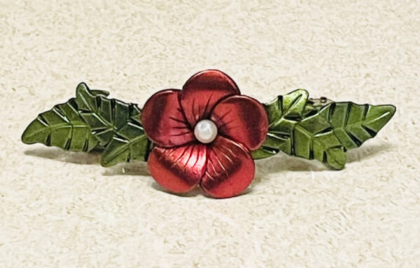 Red chrome color flower barrette with green leaves.
