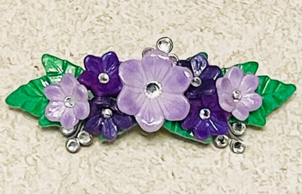 Purple clay flowers barrette with rhinestones and green leaves.